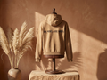WOVYN Becoming Collection Hoodie - Soft Sand in a styled interior, back view with Sanskrit embroidery “यत् भावो – तत् भवति”