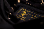 Inside-neck detail of the Obsidian Black hoodie showing WOVYN woven label, metal eyelets, and monogram hood lining
