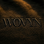 Macro detail of tonal WOVYN embroidery on the Obsidian Black hoodie, showing heavyweight fleece texture